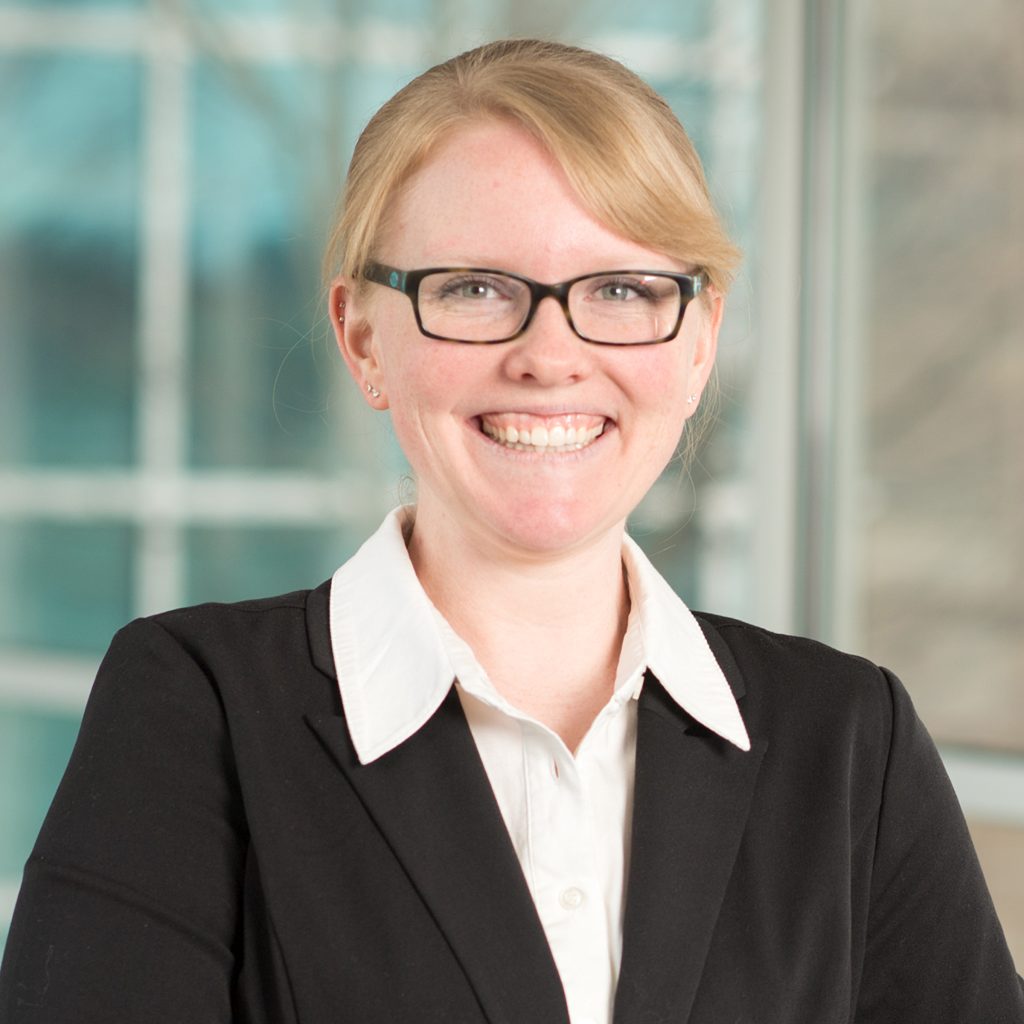 Grace Christensen smiles. Grace wears a white button up and suit.