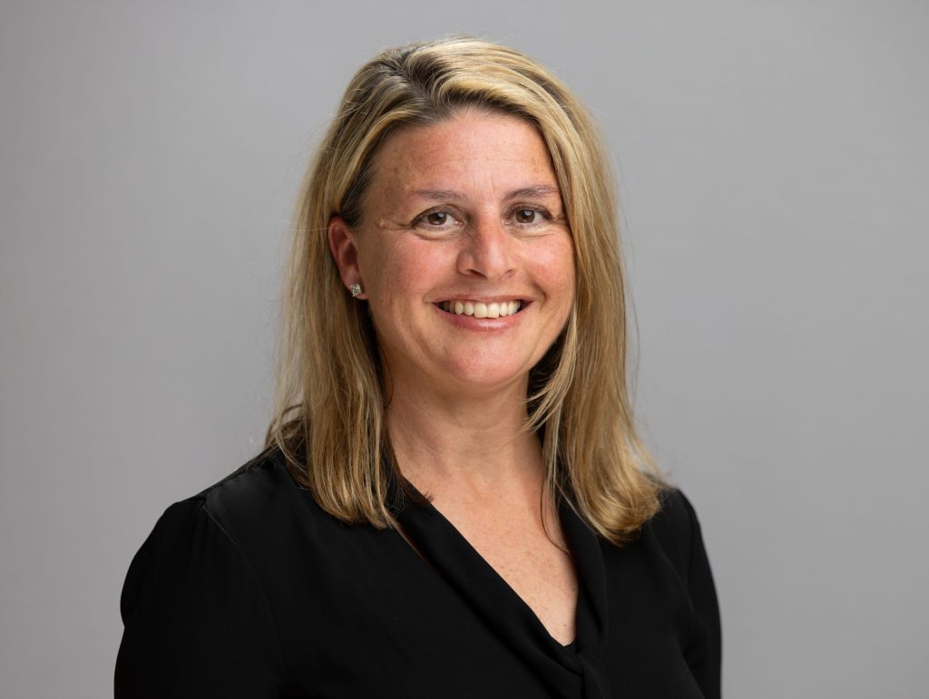 Natalia smiles. She has blond hair and wears black.