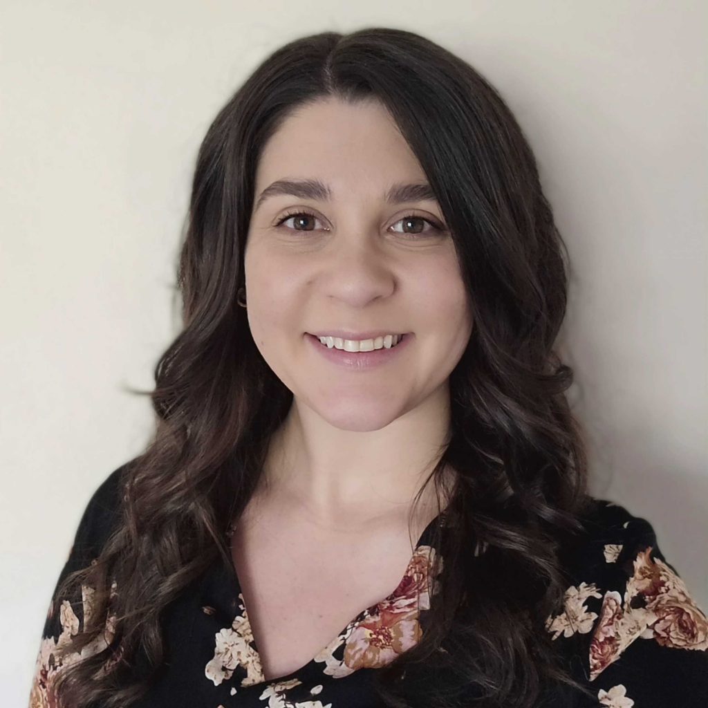 Kelsie smiles. Kelsie has long, curly brown hair.