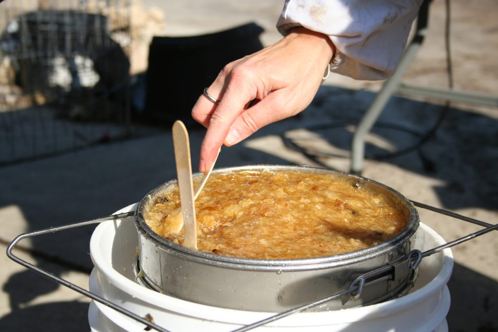 A person stirs the honey in a strainer.