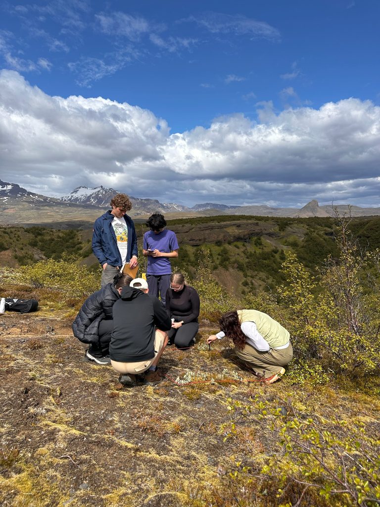 A group of people conduct field work in a mountainous region.