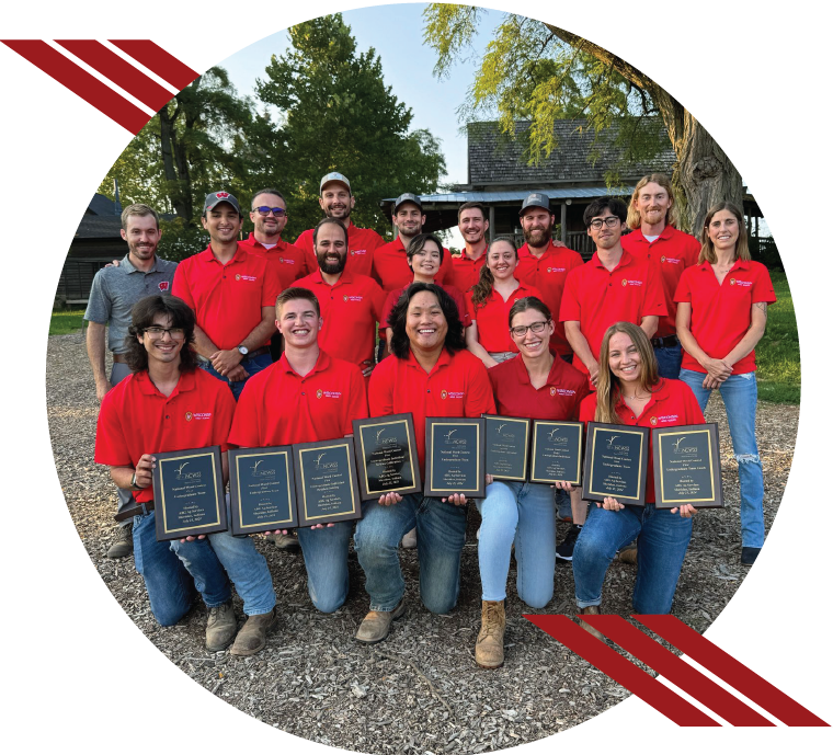 Circular image of a group of students, staff, and faculty wearing red polos with awards.