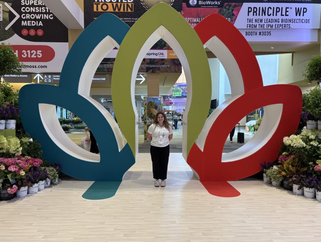 Madison Kraus stands in the middle of a large sculpture surrounded by flowers.