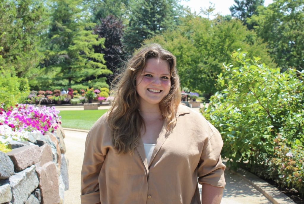 Madison Kraus smiles outside in a garden.