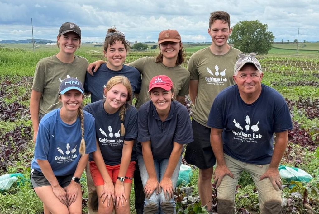 Two rows of people pose for a picture in a field.