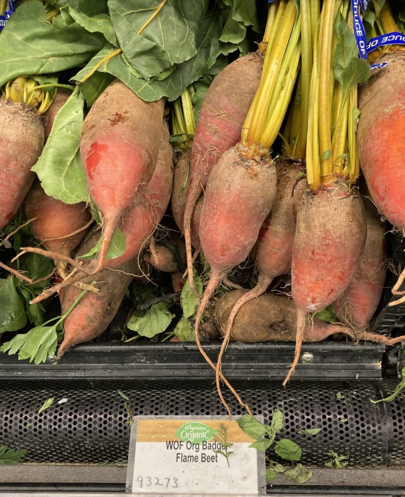 Badger flame beets are placed in bunches on a produce shelf.