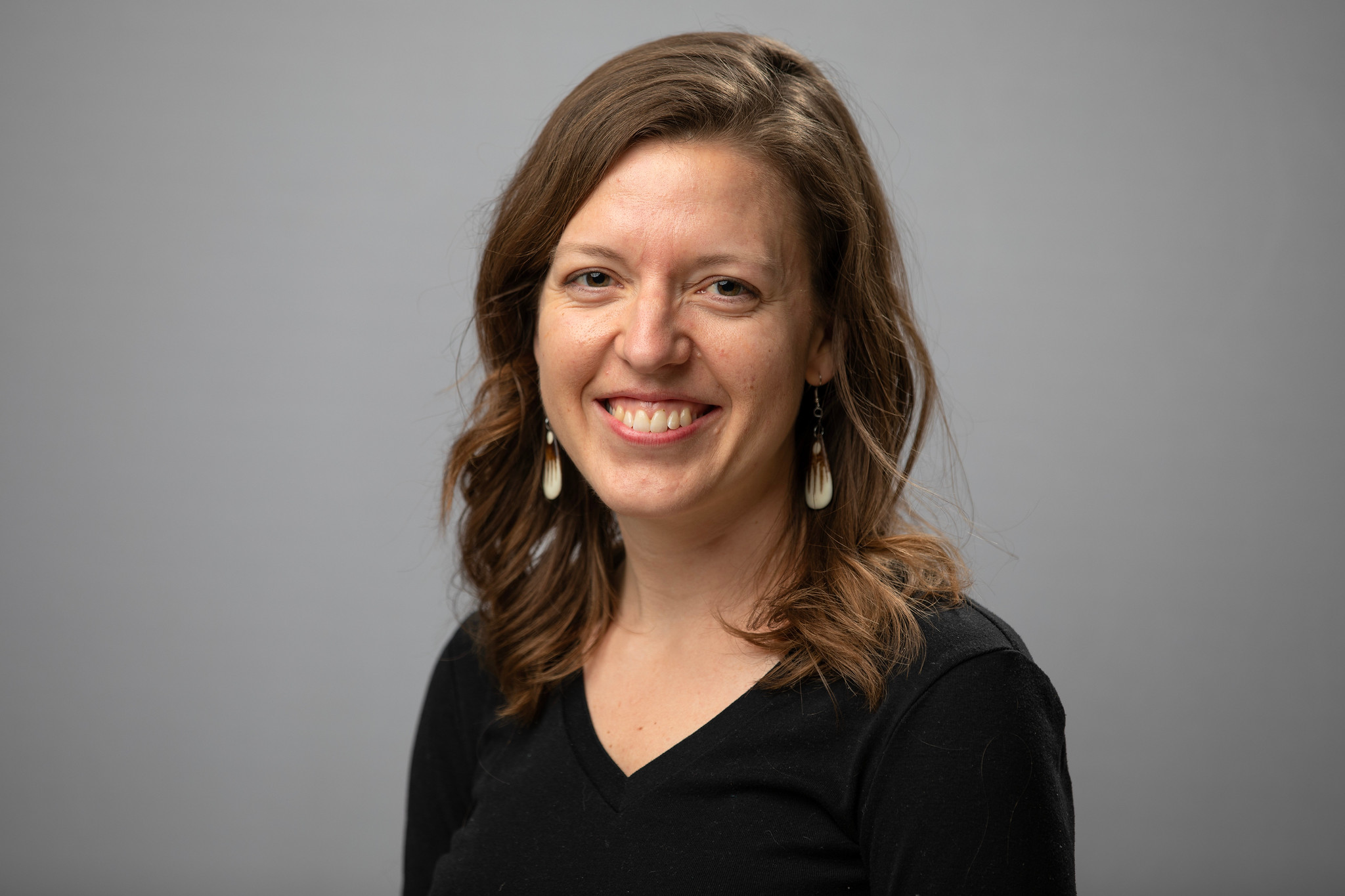 Tera smiles. Tera has curled, brown hair and wears a sweater.