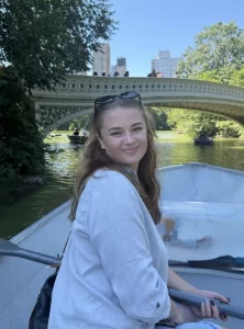 Anna Moss smiles on a row boat near a bridge.