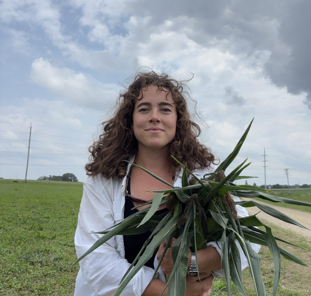 Sophie holds corn outdoors on a partially cloudy day.